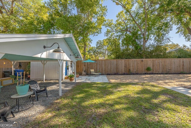 view of yard featuring a fenced backyard, an outbuilding, and a patio area