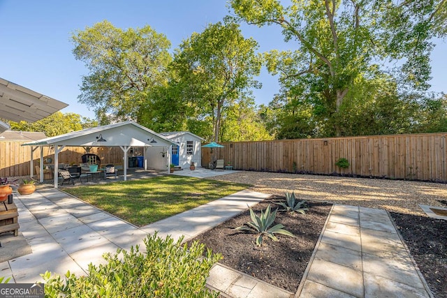 view of yard featuring an outdoor structure, a patio, and a fenced backyard