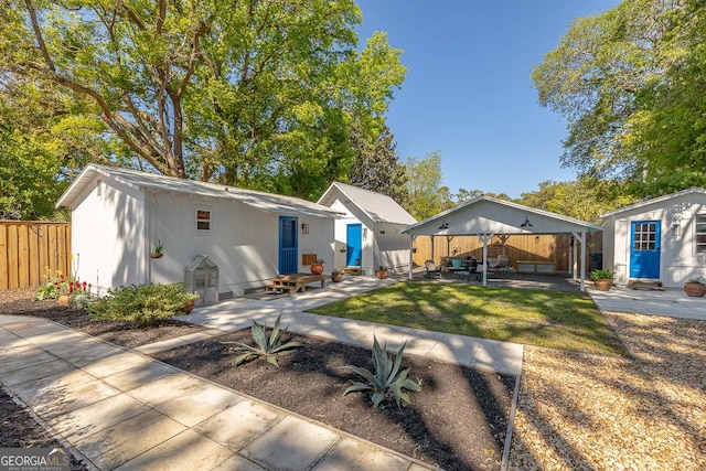 rear view of property featuring an outbuilding, fence, a patio area, entry steps, and a yard