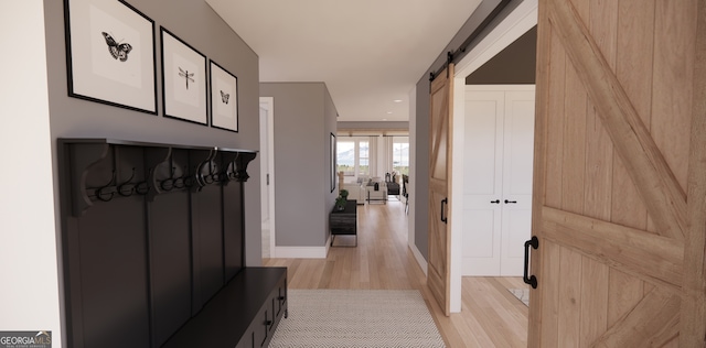 mudroom featuring a barn door, baseboards, light wood-style floors, and recessed lighting