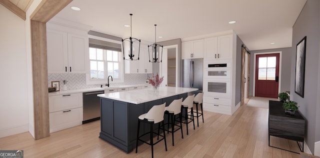 kitchen featuring stainless steel appliances, a breakfast bar, backsplash, and white cabinetry