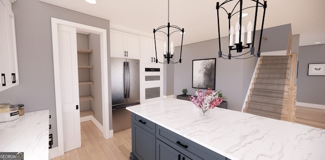 kitchen with white cabinets, light wood-style flooring, a chandelier, open shelves, and light stone countertops