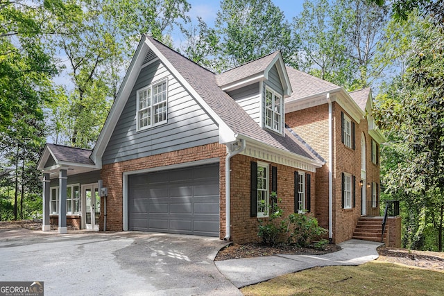 view of home's exterior with a garage, a shingled roof, brick siding, and driveway