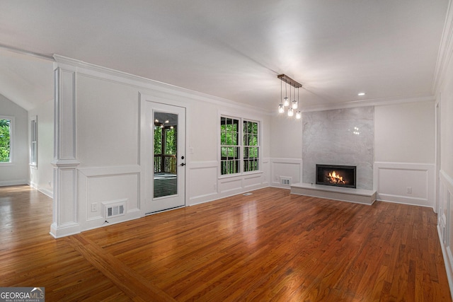 unfurnished living room featuring a premium fireplace, a decorative wall, visible vents, and wood finished floors