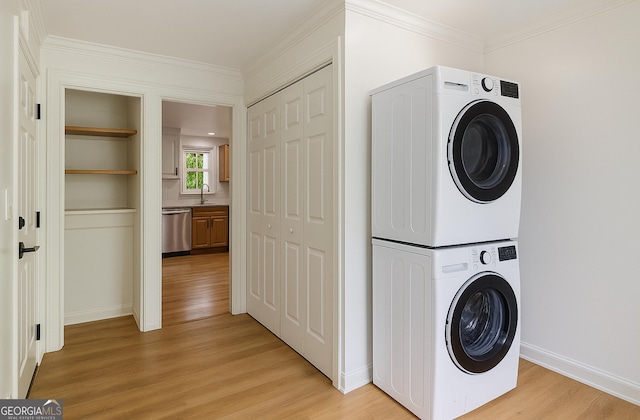 535 Emerald Pkwy, Sugar Hill, GA 30518 - washroom with stacked washer and clothes dryer, light wood-type flooring, baseboards, and crown molding