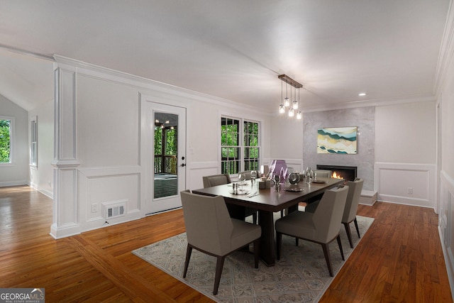 535 Emerald Pkwy, Sugar Hill, GA 30518 - dining space with plenty of natural light, a decorative wall, a large fireplace, wood finished floors, and crown molding
