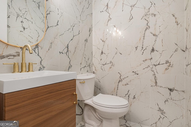 half bath featuring toilet, marble finish floor, and vanity