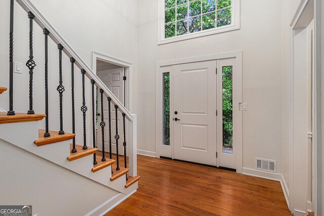 foyer entrance featuring wood finished floors, baseboards, a healthy amount of sunlight, and visible vents