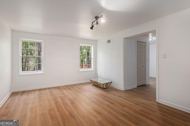 empty room with light wood-type flooring, visible vents, and baseboards