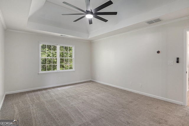 carpeted spare room with visible vents, ceiling fan, crown molding, a raised ceiling, and baseboards