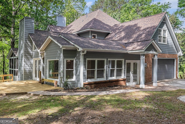 view of front facade featuring a chimney, french doors, a garage, concrete driveway, and roof with shingles