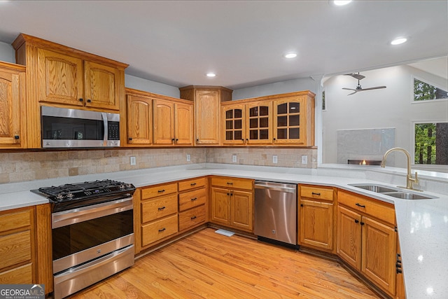 kitchen featuring light countertops, stainless steel appliances, light wood-style flooring, and a sink