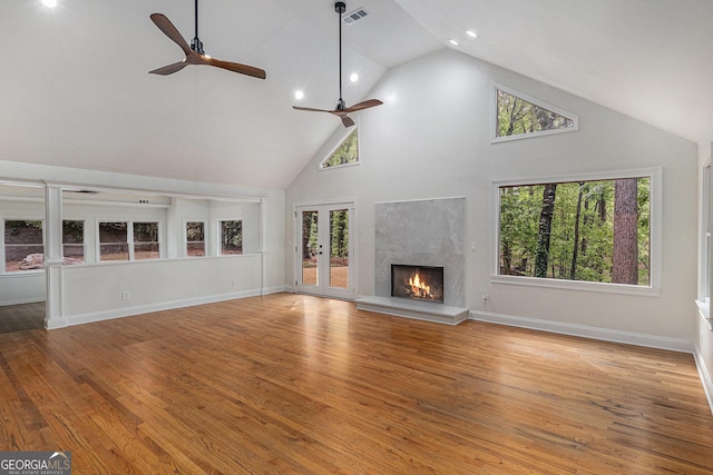 unfurnished living room with a premium fireplace, ceiling fan, high vaulted ceiling, and a wealth of natural light