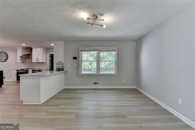 780 N Ola Rd, Mcdonough, GA 30252 - kitchen featuring wall chimney exhaust hood, a textured ceiling, stainless steel range with electric cooktop, visible vents, and light wood-style floors