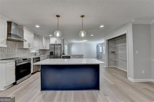780 N Ola Rd, Mcdonough, GA 30252 - kitchen with light wood finished floors, a sink, wall chimney range hood, a kitchen island, and appliances with stainless steel finishes