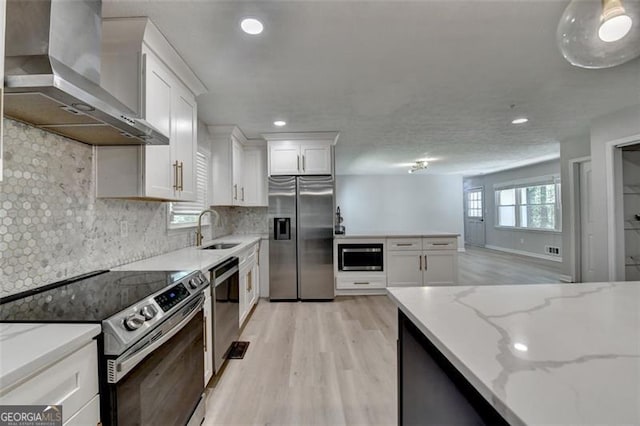 780 N Ola Rd, Mcdonough, GA 30252 - kitchen featuring a sink, white cabinetry, light wood-style floors, wall chimney range hood, and appliances with stainless steel finishes