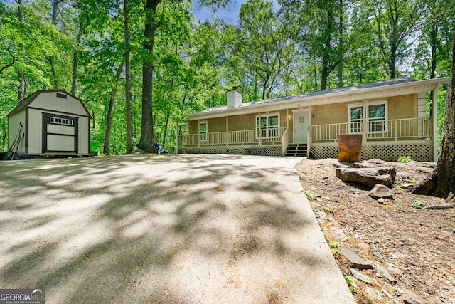507 Lakeshore Dr, Stockbridge, GA 30281 - view of front of property featuring a chimney, a storage shed, stucco siding, an outbuilding, and covered porch