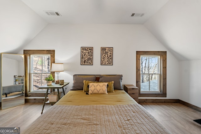 bedroom with lofted ceiling, visible vents, and wood finished floors