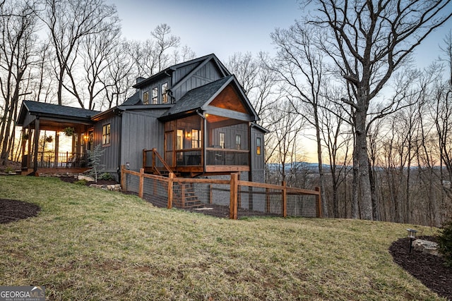 rear view of property featuring a lawn, roof with shingles, and board and batten siding
