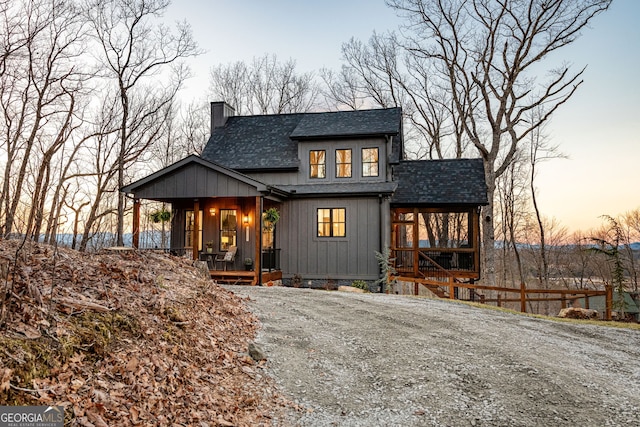 view of front of home with a porch, a chimney, roof with shingles, and board and batten siding