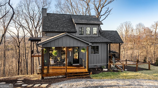exterior space with board and batten siding, roof with shingles, and a chimney