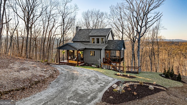 chalet / cabin featuring a chimney, a porch, a shingled roof, and a front yard