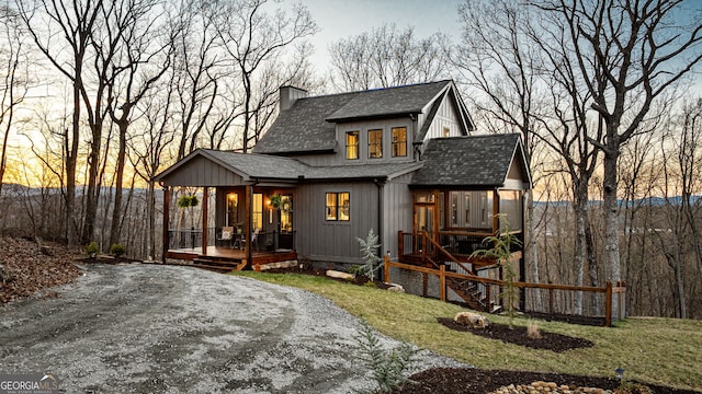 exterior space featuring a lawn, a chimney, covered porch, and roof with shingles