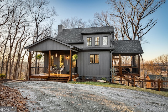 view of front of property with stairway, a shingled roof, a chimney, and covered porch