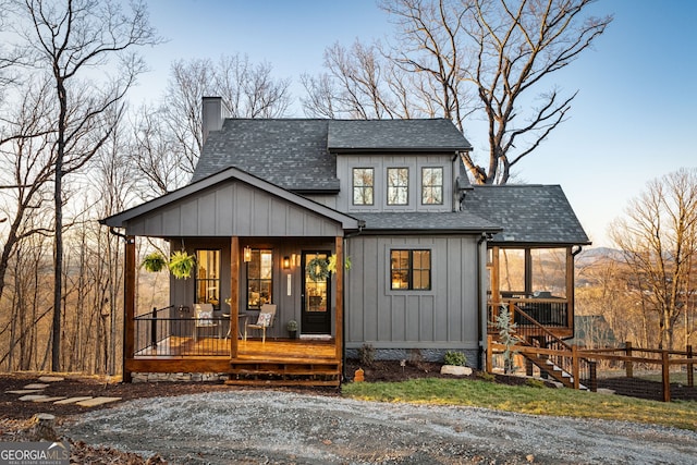 rear view of property featuring a porch, a shingled roof, a chimney, and stairway