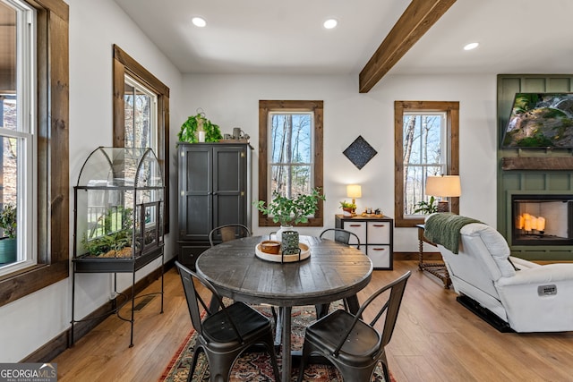 dining room featuring recessed lighting, light wood-type flooring, beam ceiling, and a fireplace