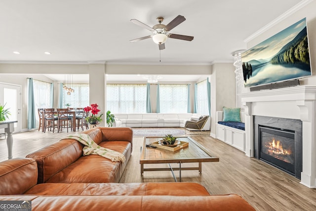 living area with recessed lighting, wood finished floors, a premium fireplace, crown molding, and ceiling fan
