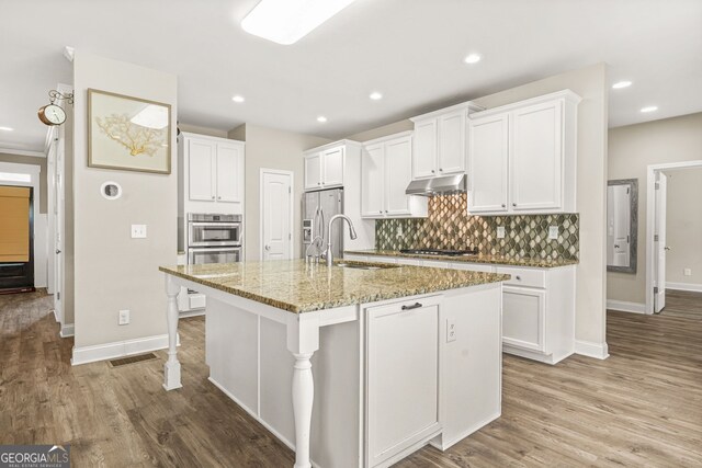 kitchen with white cabinets, baseboards, a sink, and backsplash