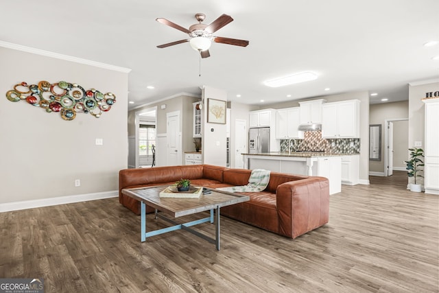 living area featuring baseboards, recessed lighting, a ceiling fan, and light wood-type flooring