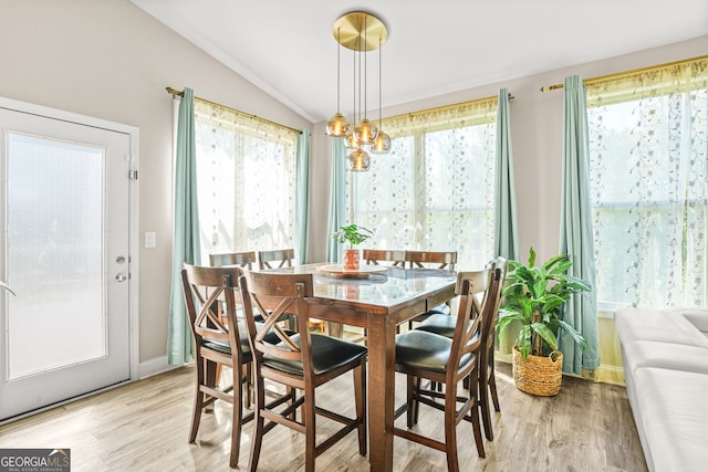 dining space with vaulted ceiling, a healthy amount of sunlight, and light wood-style flooring