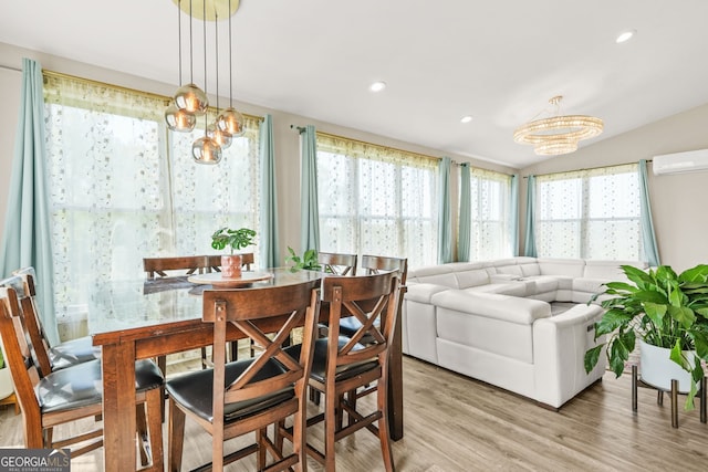 dining space featuring light wood-type flooring, a wealth of natural light, a notable chandelier, and a wall mounted air conditioner