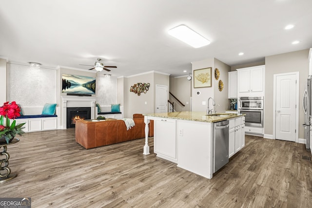 kitchen with a sink, white cabinetry, wood finished floors, ceiling fan, and appliances with stainless steel finishes