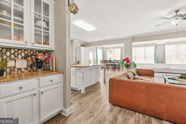 interior space with ornamental molding, a ceiling fan, light wood-style floors, and recessed lighting