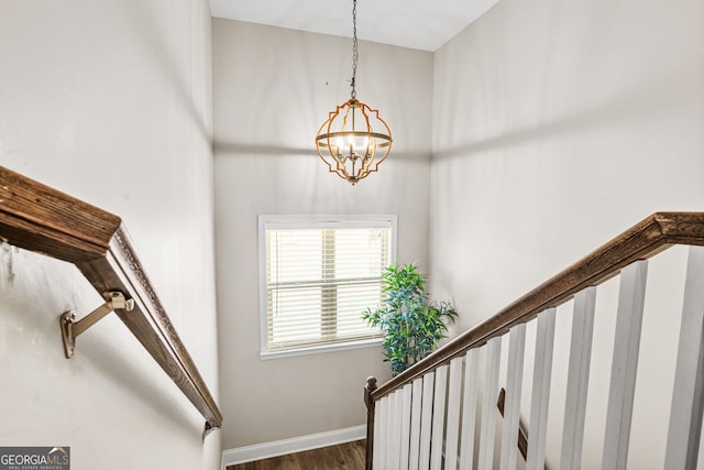 staircase with a chandelier and wood finished floors