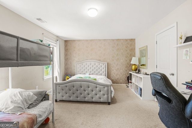 carpeted bedroom with an accent wall and visible vents