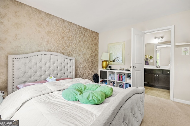 bedroom with wallpapered walls, a sink, ensuite bath, baseboards, and light colored carpet