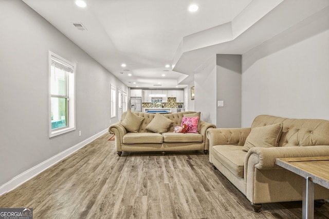 living room featuring recessed lighting, visible vents, indoor bar, light wood-type flooring, and baseboards