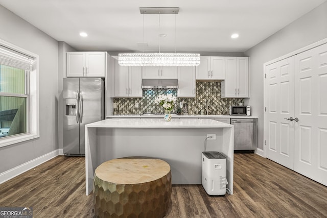 kitchen featuring stainless steel appliances, a center island, under cabinet range hood, and dark wood-style flooring