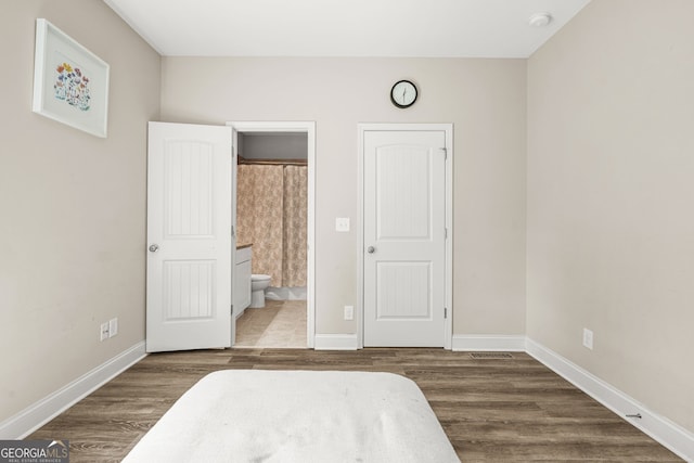 bedroom with wood finished floors, baseboards, and ensuite bathroom