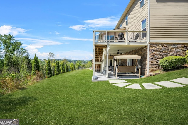 view of yard with ceiling fan, a patio, and a balcony