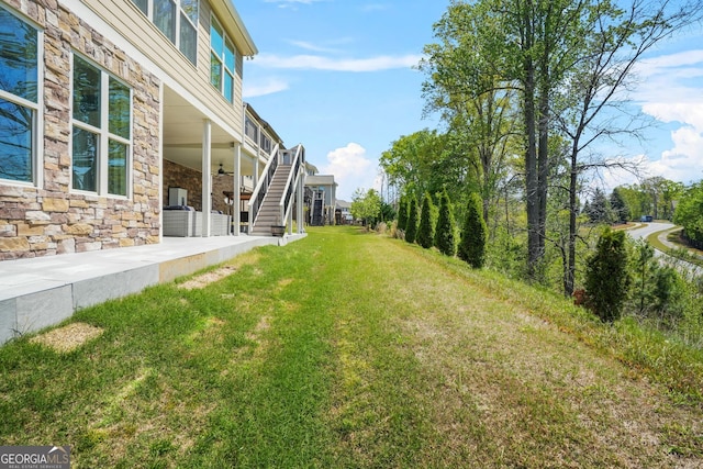 view of yard with stairway, a patio area, and ceiling fan