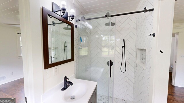 full bathroom featuring a shower stall, vanity, wood finished floors, crown molding, and baseboards