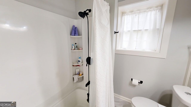 full bath with marble finish flooring, toilet, and shower / bath combination with curtain