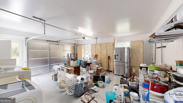 garage with stainless steel fridge with ice dispenser, washer / clothes dryer, and a garage door opener