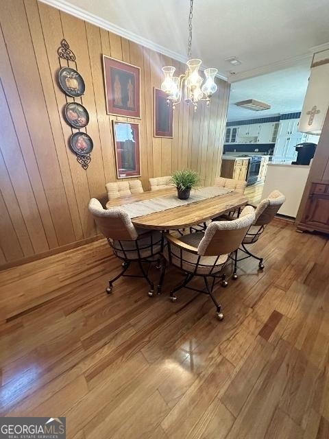 dining space featuring an inviting chandelier, ornamental molding, and wood finished floors
