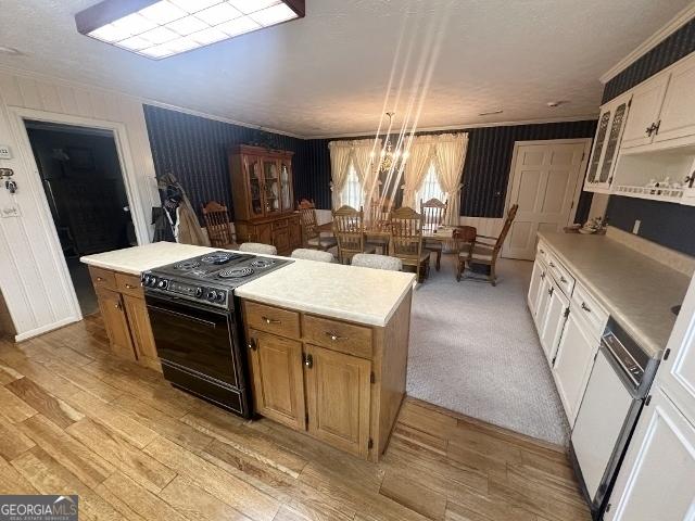 kitchen with black range with electric cooktop, crown molding, light wood-style flooring, and light countertops